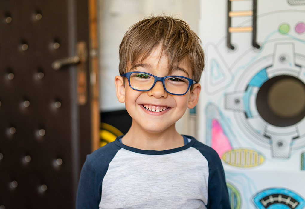 Portrait of happy caucasian boy with eyeglasses standing at home